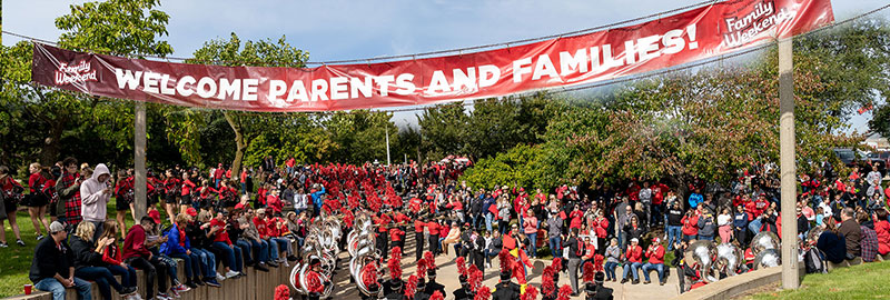 Students and family under the Family Weekend event banner.